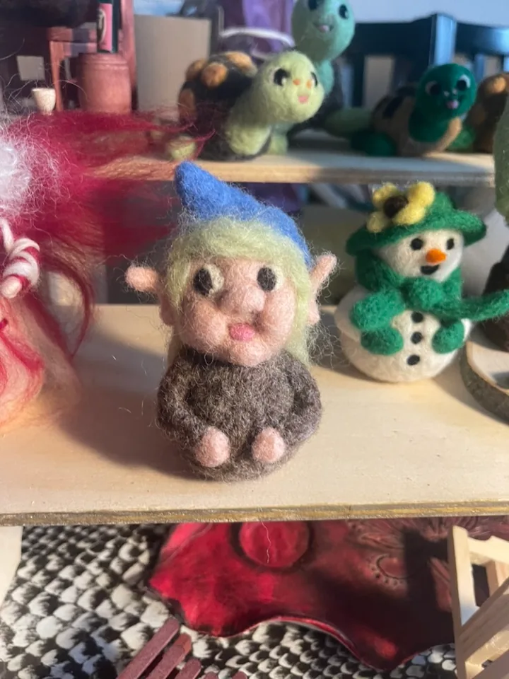 Eine sitzende Figur mit blauer Mütze und großen Ohren.