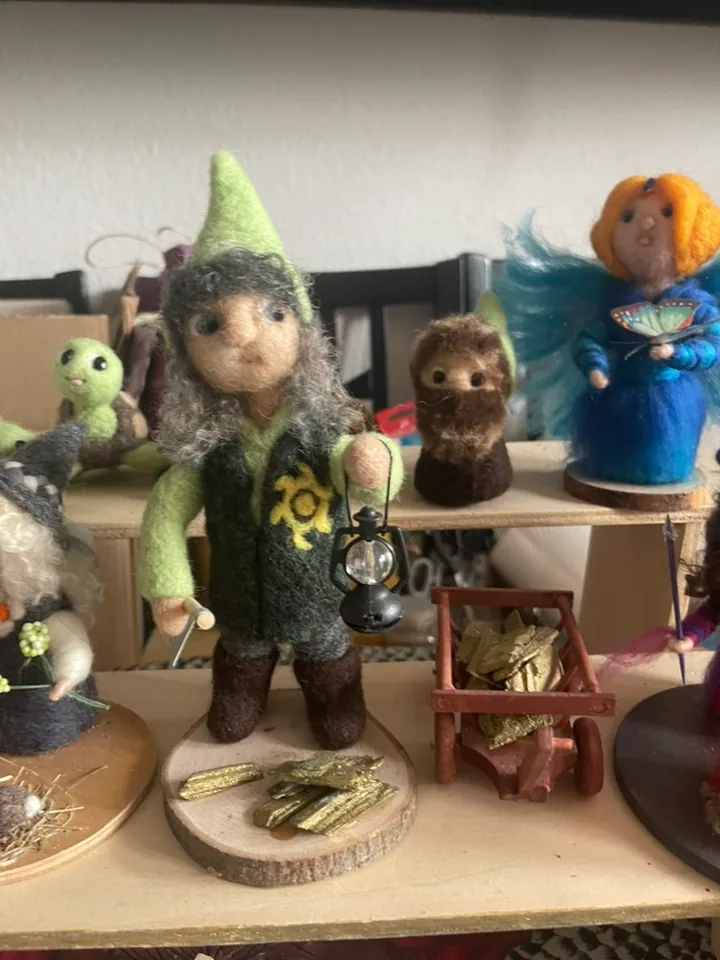 Eine Figur mit Laterne, Holzkarre und grünem Hut.