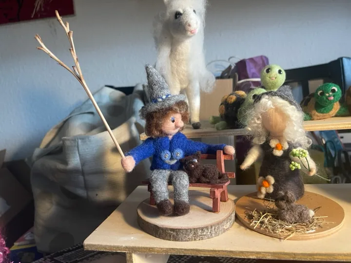 Zwei Figuren mit Bank und tierischen Begleitern.
