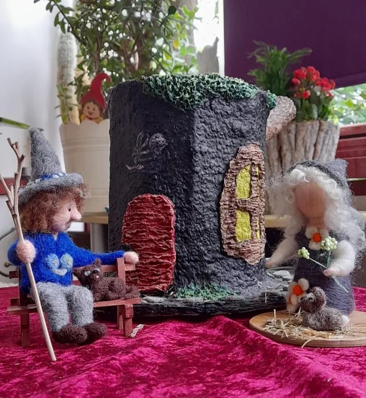 Zwei Figuren vor einem fantasievoll gestalteten Haus.